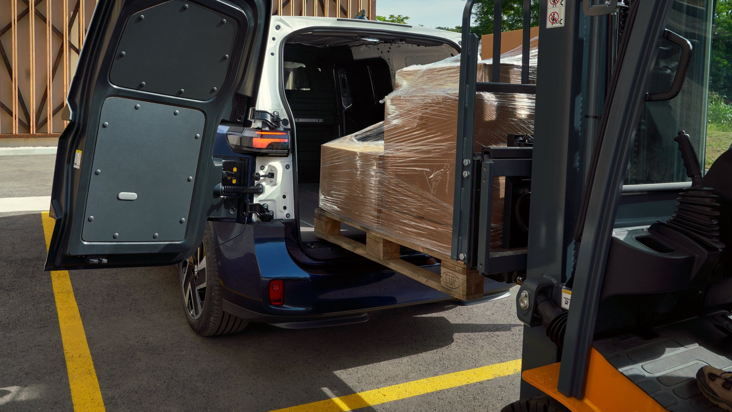 Ein weiß blauer ID. Buzz Cargo mit Heckflügeltüren wird mit einem Gabelstapler beladen