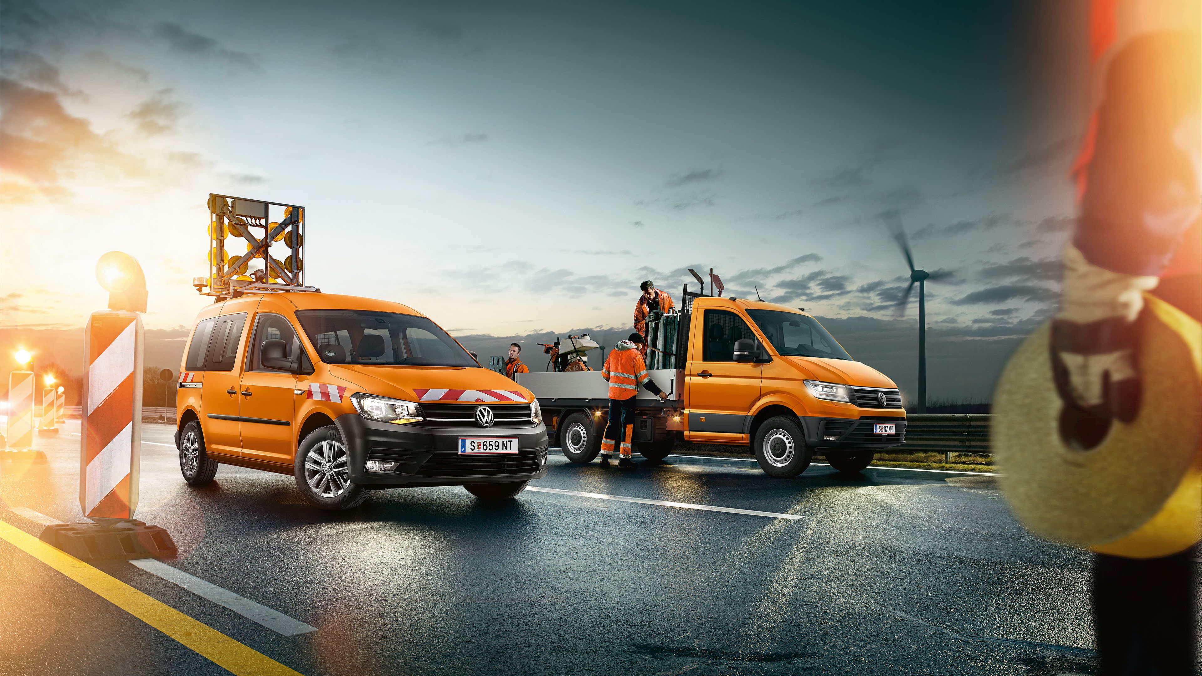 Zu sehen ist ein VW Crafter Pritschenwagen der gerade von Straßenarbeitern beladen wird. 