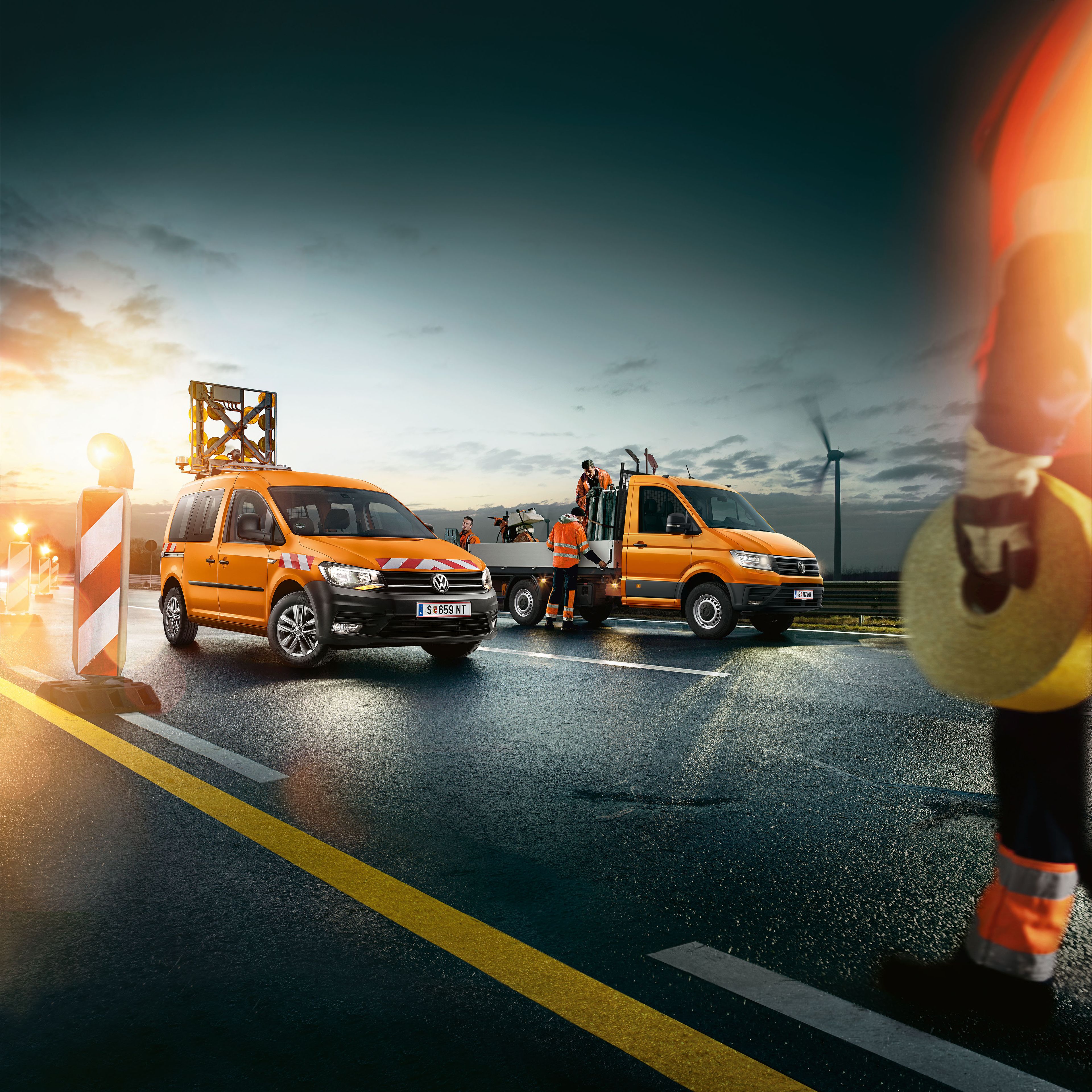 Zu sehen ist ein VW Crafter Pritschenwagen der gerade von Straßenarbeitern beladen wird. 