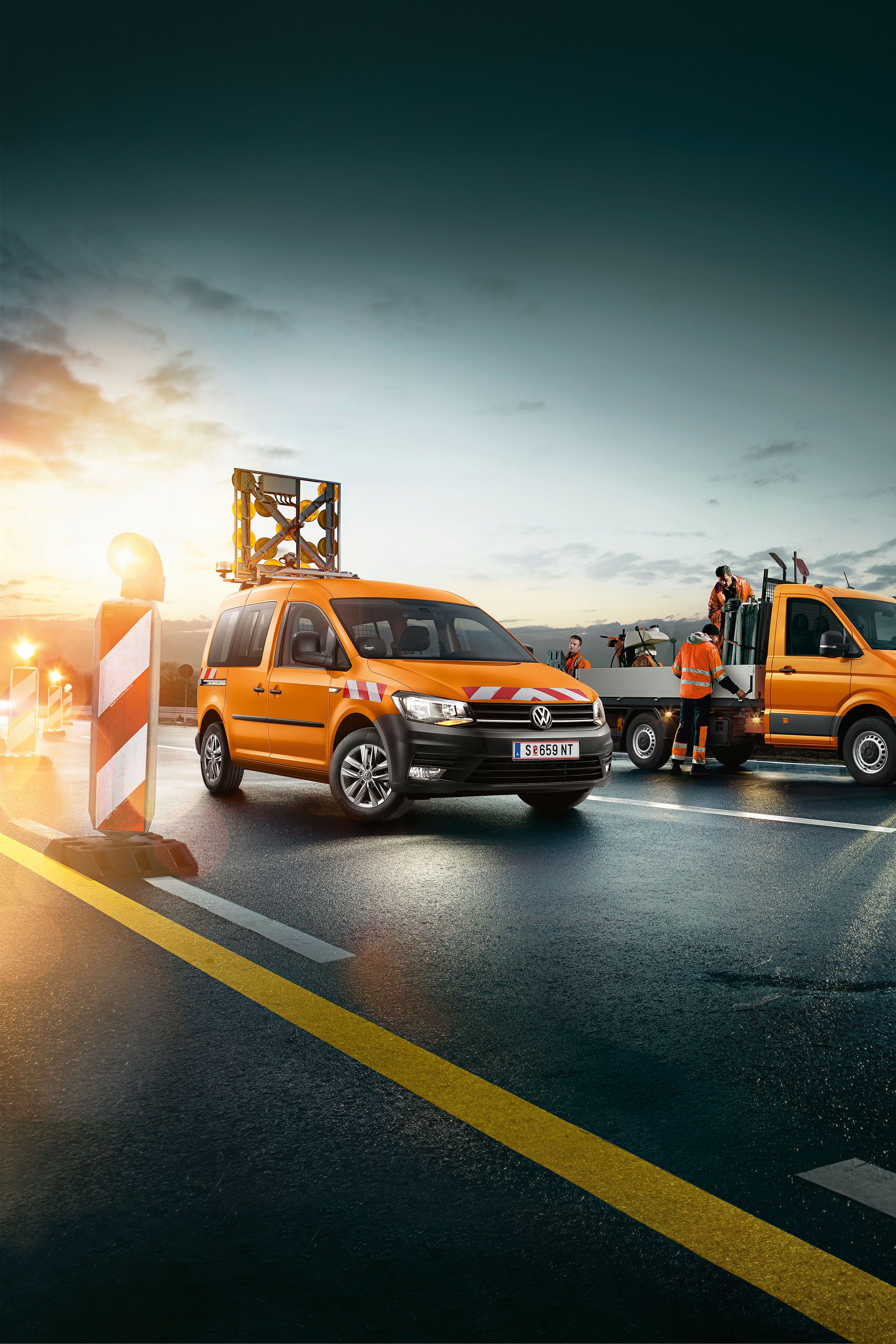 Zu sehen ist ein VW Crafter Pritschenwagen der gerade von Straßenarbeitern beladen wird. 