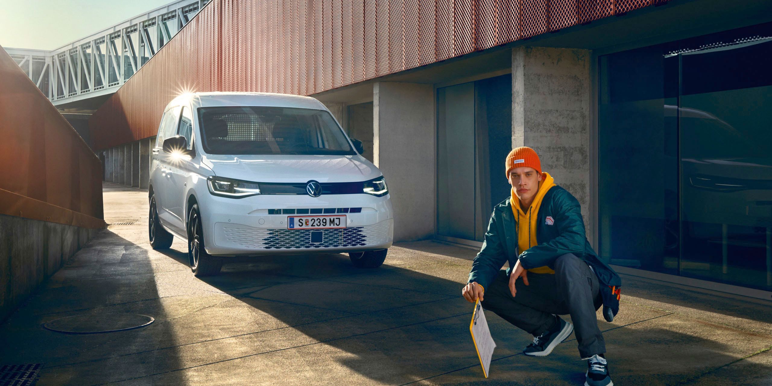 Weißer VW Caddy Kastenwagen fährt durch Stadt