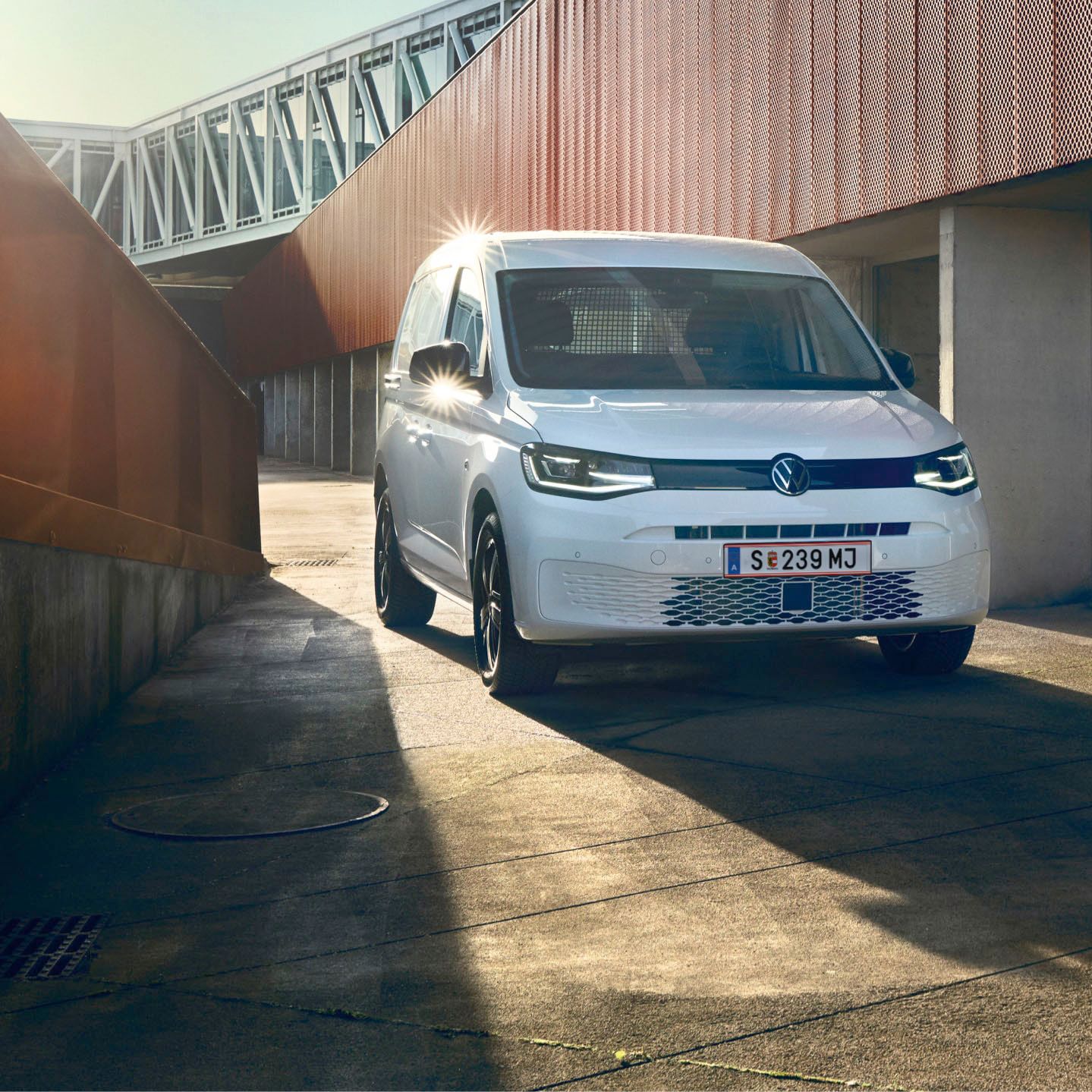 Weißer VW Caddy Kastenwagen fährt durch Stadt