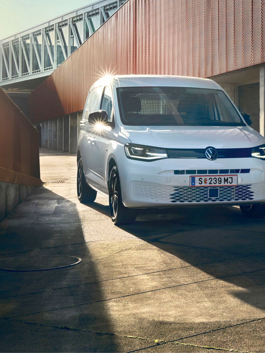 Weißer VW Caddy Kastenwagen fährt durch Stadt