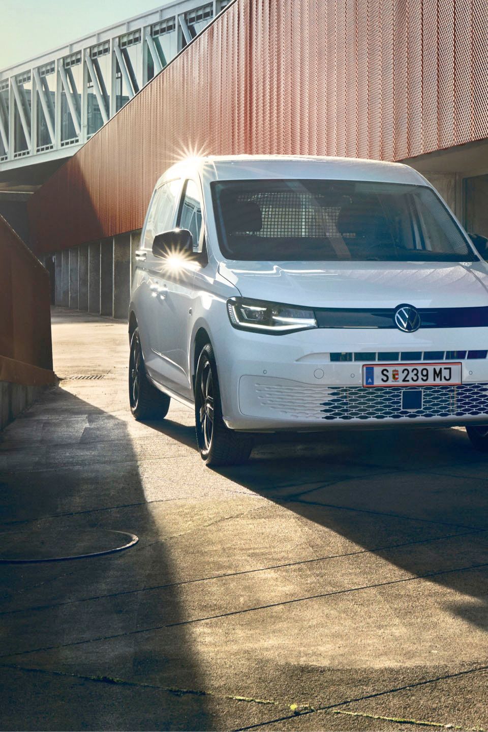 Weißer VW Caddy Kastenwagen fährt durch Stadt