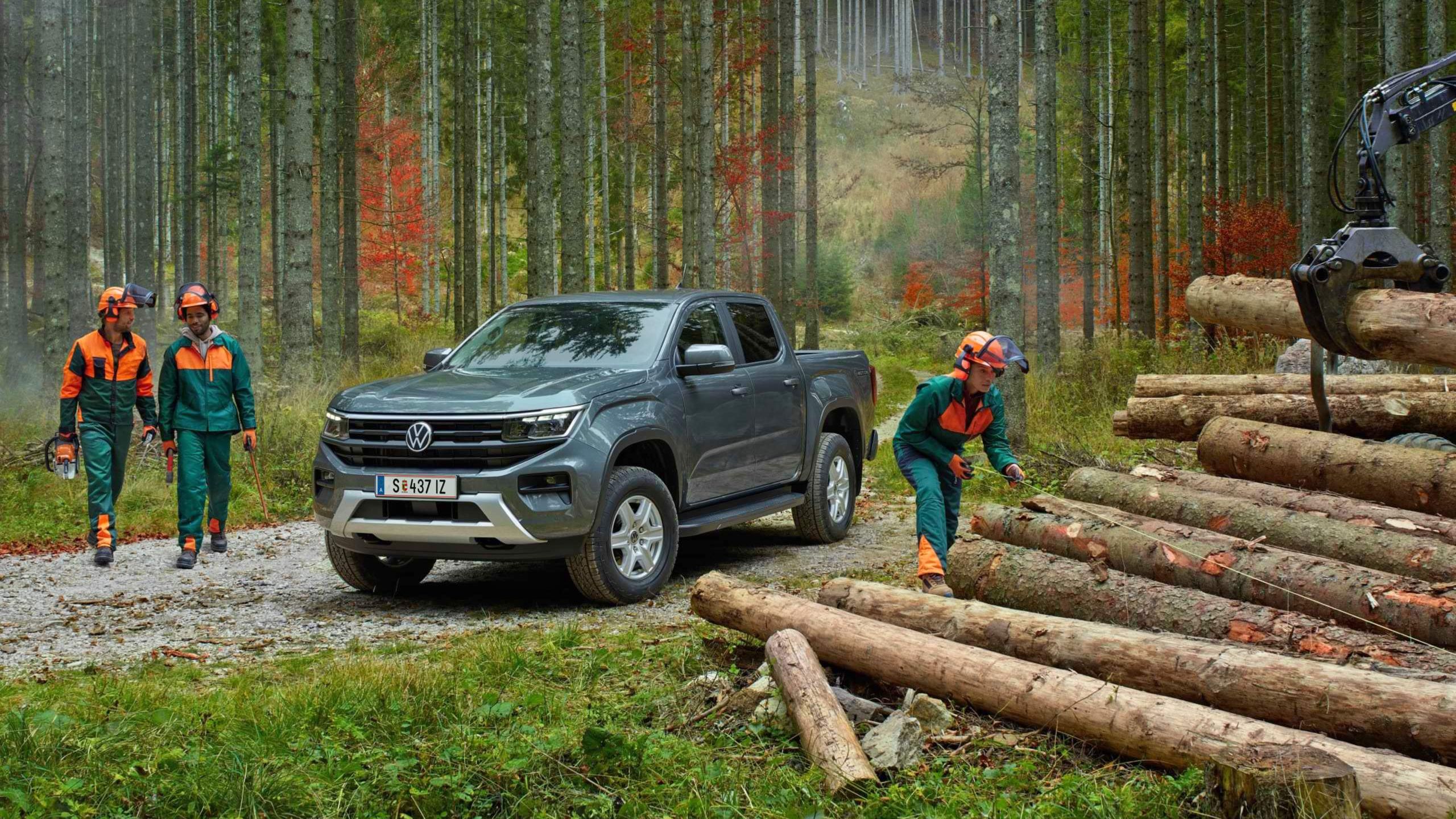 Ein VW Amarok Life steht in einem Wald und man sieht mehrere Förster bei Holzarbeiten