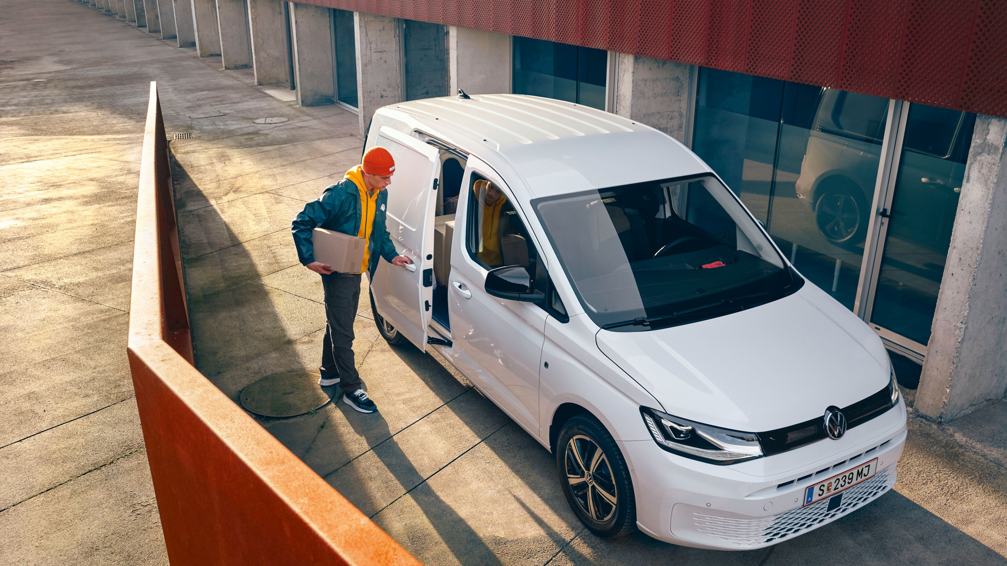 Ein Lieferant öffnet die Tür eines weißen VW Caddy Cargo 