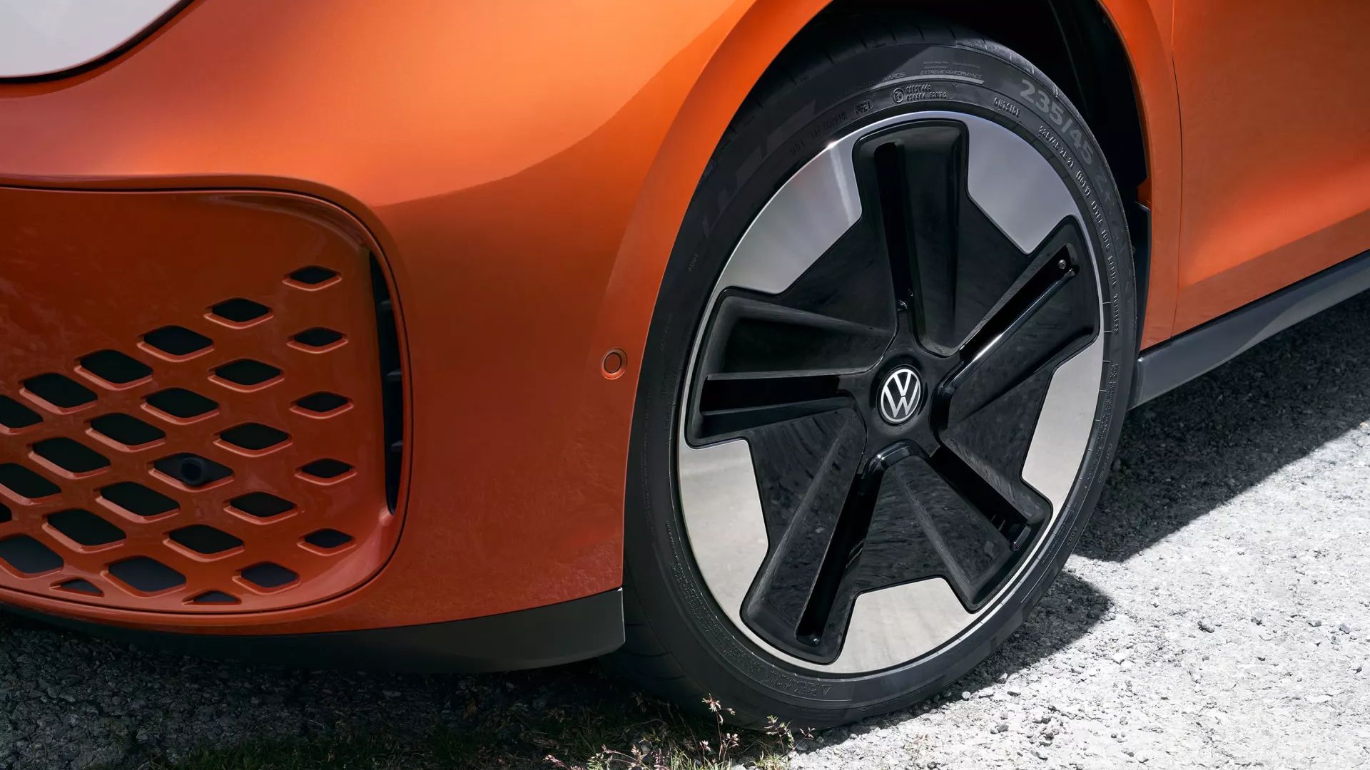 Das Rad und Felge eines orangen VW ID. Buzz steht im Vordergrund.